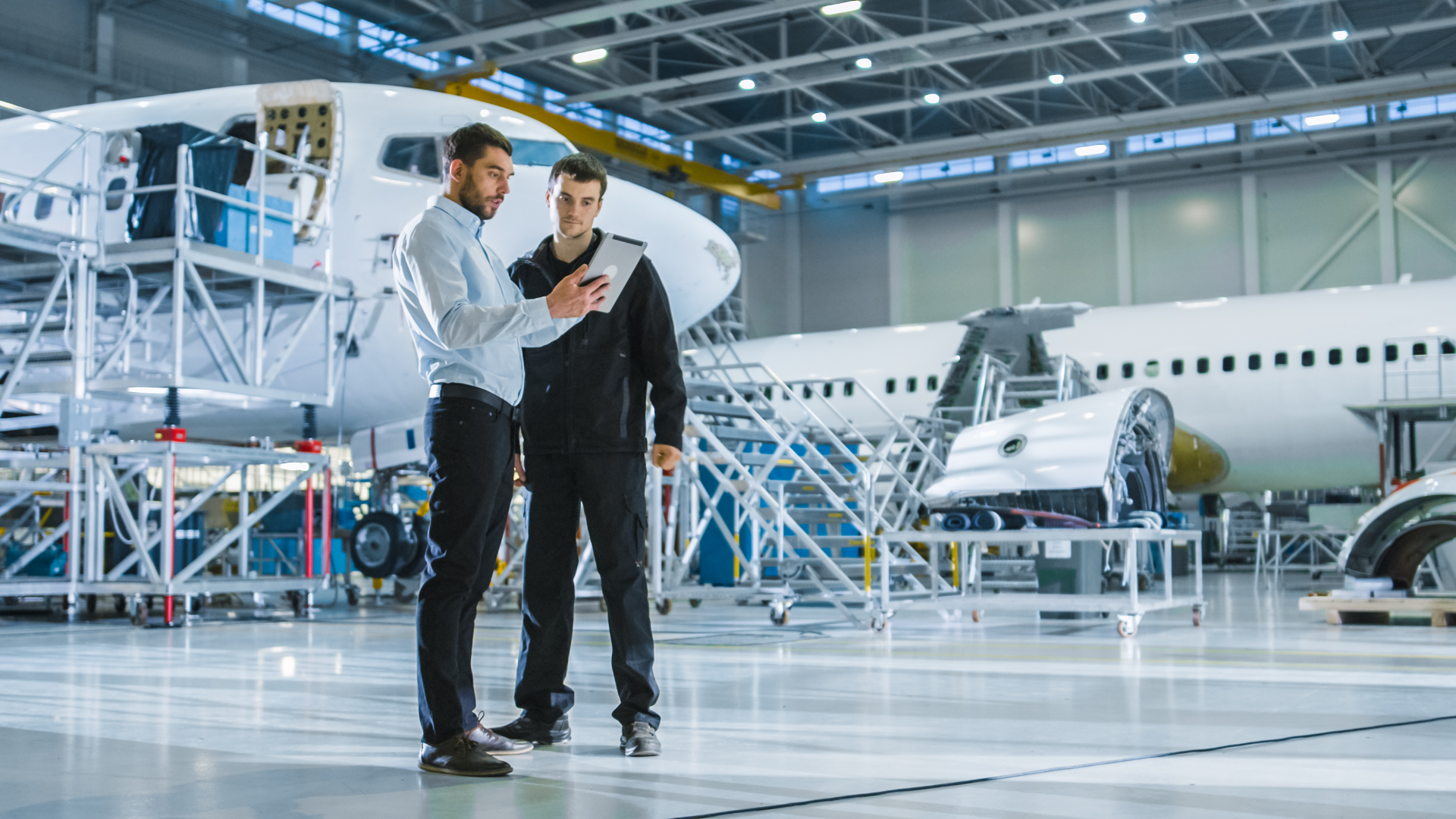 Engineers reviewing data on a tablet inside an aerospace hangar